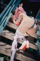 A woman with pink hair is posing on a wooden staircase.