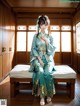 A woman in a blue kimono sitting on a bench.