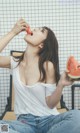 A woman sitting on a chair eating a slice of watermelon.