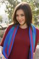 A woman in a red shirt and blue scarf posing for a picture.