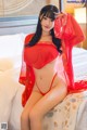 A woman in a red lingerie sitting on a bed.