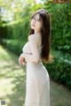 A woman in a white dress standing in the grass.