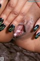 A close up of a woman's hand with a black and green manicure.