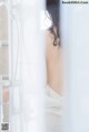 A woman standing in a shower with her back to the camera.