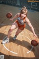 A woman in an orange uniform dribbling a basketball on a court.