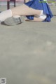 A woman in a blue and white uniform is sitting on the ground.