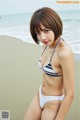 A woman in a bikini sitting on a beach.