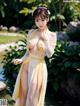 A woman in a white and yellow dress posing by a pond.